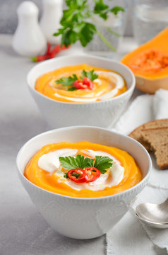Pumpkin soup with cream and parsley on a grey concrete or stone background, selective focus