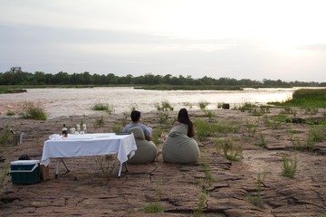 Indian couple at sunset next to a river in Selous Game Reserve, Tanzania