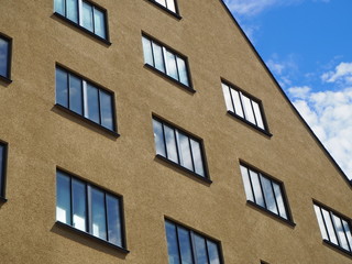 Fototapeta na wymiar Hauswand beige mit Fenstern und spiegelnder Himmel