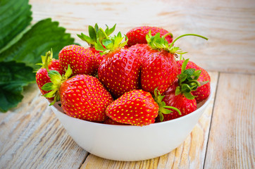 Red strawberries on a light wooden table.