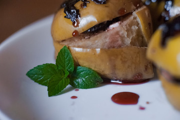 Baked apples with cottage cheese, chocolate, nuts, mint. Apples on a white plate