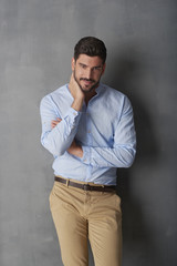 Obraz premium Confident young man standing at grey wall in the studio.
