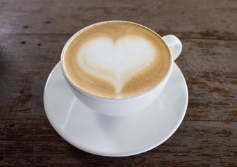 Hot coffee on table with heart shape on top of white cup.