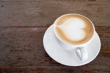 Hot coffee on table with heart shape on top of white cup. Copy space.