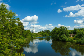 Summer landscape in Suzdal with river, temple on the hill and beautiful clouds in the sky.