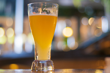 Glass of light beer with blurred light background in a pub
