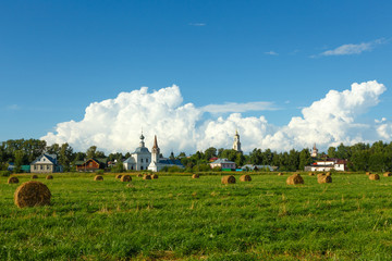Suzdal, Russia. Field with haystacks, old temples and beautiful clouds in the sky.