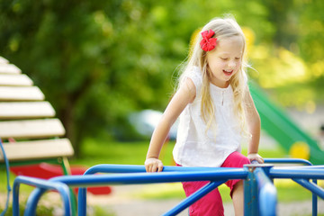 Cute little girl having fun on a playground outdoors in summer.