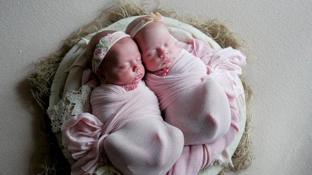 Twin Babies Sleep In The Crib In Dresses And Headband