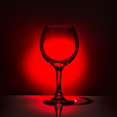 Fototapeta na wymiar beautiful silhouette empty wine glass on red and black background, close up