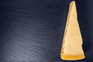 top view of single tasty fresh yellow big segment piece parm on stone slate background, close up