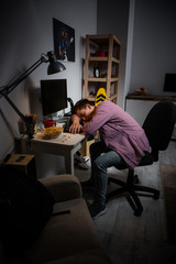 Teenage boy sleeping in front of computer. Boy falling asleep at the computer table, problem with computer addiction.
