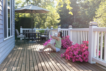 Woman hugging her dog while outdoors on home deck