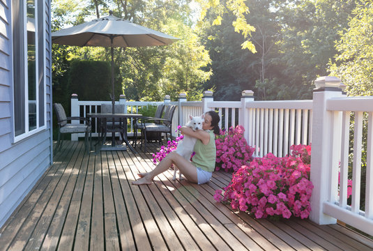 Woman Hugging Her Dog While Outdoors On Home Deck