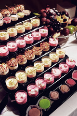 Desserts in glasses on catering table, toned