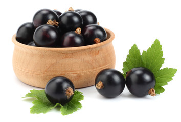 black currant in wooden bowl with green leaf isolated on white background
