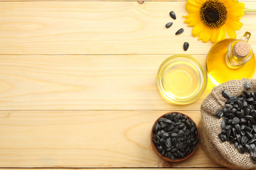 Sunflower oil in glass jug , seeds and flower on light wooden background. top view with copy space