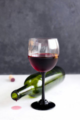 A glass of red wine on black background with bunch of grapes