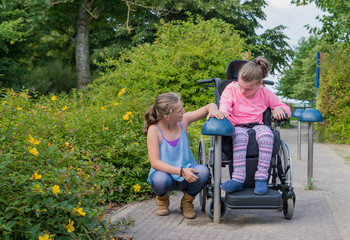 Working together with disability, a disabled child relaxing outside with her sister