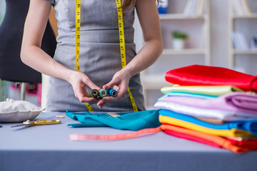 Woman tailor working on a clothing sewing stitching measuring fa
