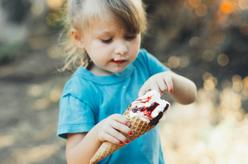 Naklejka premium Beautiful girl five years eating ice cream in nature