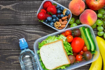 Gordijnen School lunch boxes with sandwich, fruits, vegetables and bottle of water and copy space © samael334