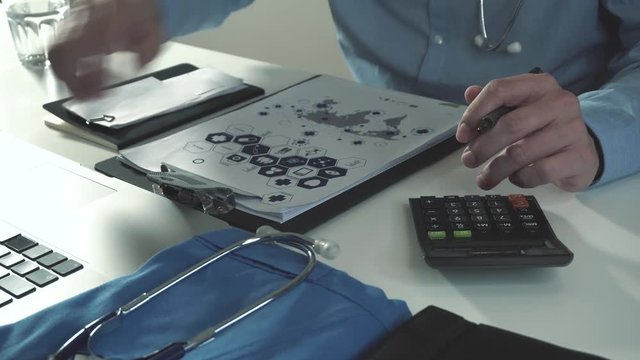 Healthcare costs and fees concept.Hand of smart doctor used a calculator for medical costs in modern hospital and drinking a glass of water in 4k(UHD)