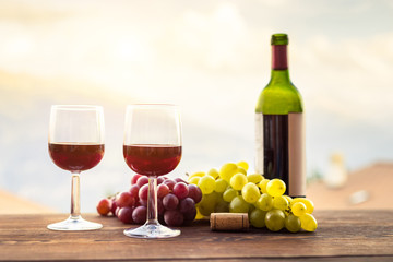 Two glasses of red wine, grape, bottle on wooden table