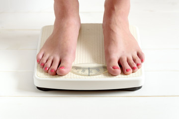 Female feet standing on a bathroom scale. Concept of diet.