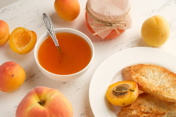 homemade jam of ripe peaches on a white wooden background