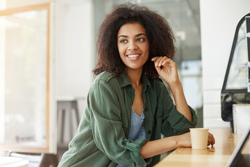 Fototapeta premium Young beautiful african girl student resting relaxing sitting in cafe smiling drinking coffee.