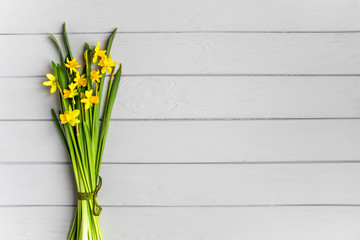 Bouquet of daffodils on grey background. Romantic minimalistic spring composition, top view, flat lay