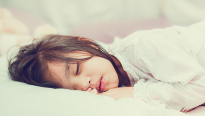 Sweet little girl is sleeping in bed at home