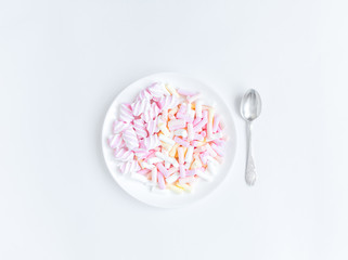 Colorful light marshmallows on a plate on white background. Top view, flat lay