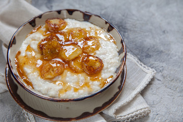 Bowl of oatmeal porridge with roasted banana and honey. healthy breakfast every day.