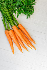 A bunch of fresh washed carrots on a white wooden table. Background of fresh vegetables with a blank space for text top view