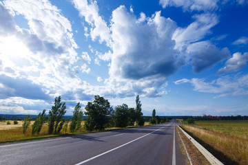 Empty asphalt highway between meadows and fields