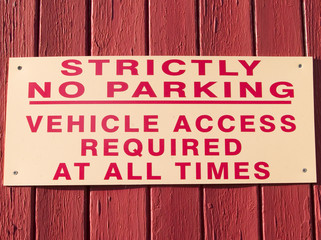 Sign fastened  to a painted wooden gate saying 'Strictly no parking Vehicle Access Required at all Times'.