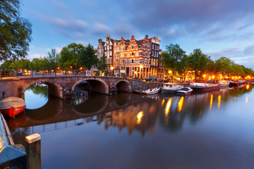 Obraz premium Kanał Amsterdamu, most i typowe domy, łodzie i rowery podczas niebieskiej godziny wieczornego zmierzchu, Holandia, Holandia. Używane tonowanie