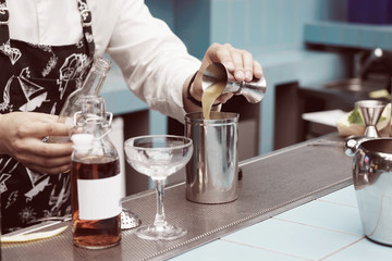 Bartender is pouring infusion into a mixing glass, toned