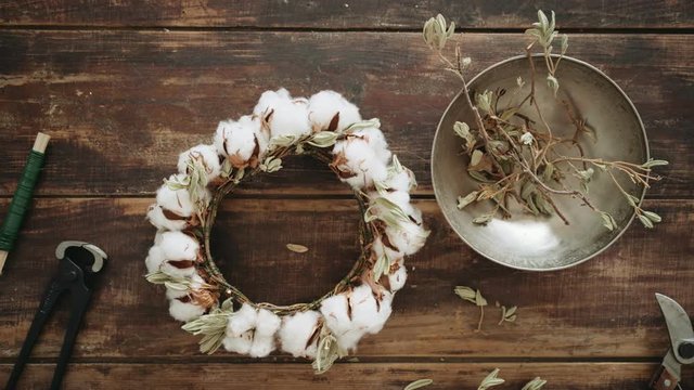 Shot of beautifully arranged set of secateurs scissors, nippers, metal decorative wire, aluminium plate with branches and cotton flower wreath for diy hand made project on top of wooden table