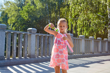 Girl with bubble blower outdoors. Child, sunny summer day.
