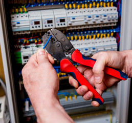 The man is repairing the switchboard voltage with automatic switches.