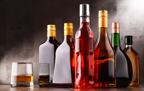 Glass and bottles of assorted alcoholic beverages.