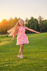 Fototapeta na wymiar Cute little girl dancing outdoors. Child and green grass.