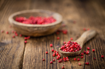 Pink Peppercorns on wooden background; selective focus