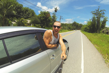 Young Happy Man Taking Selfie Picture with Smartphone on Monopod Stick. Hipster Making Road Trip...