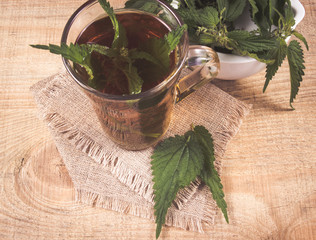 Healing tea with nettle. Tea in a glass cup on a wooden table. The source of vitamins.