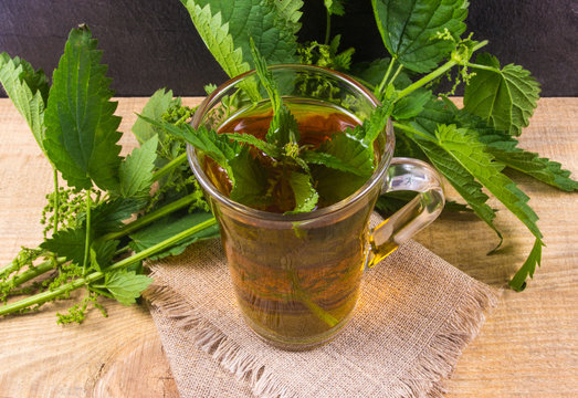 Healing tea with nettle. Tea in a glass cup on a wooden table. The source of vitamins.