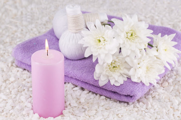 Fototapeta na wymiar Spa. Still life. Candle of pink color, a towel and white flowers on a background of white pebbles.